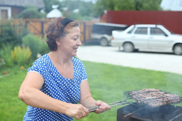 Olgun kadın bahçede Barbekü yemek — Stok fotoğraf