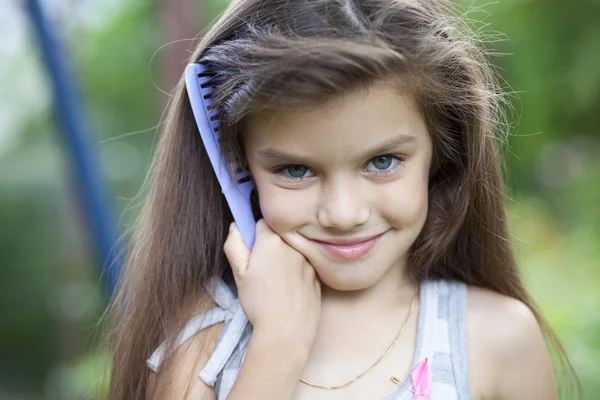 Little girl holding a comb in his hand — Stock Photo, Image