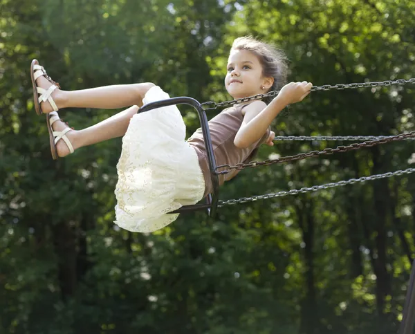 Щаслива маленька дівчинка катається на гойдалці в парку — стокове фото