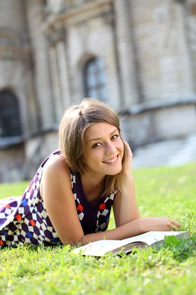 Ung vacker tjej läser en bok utomhus — Stockfoto