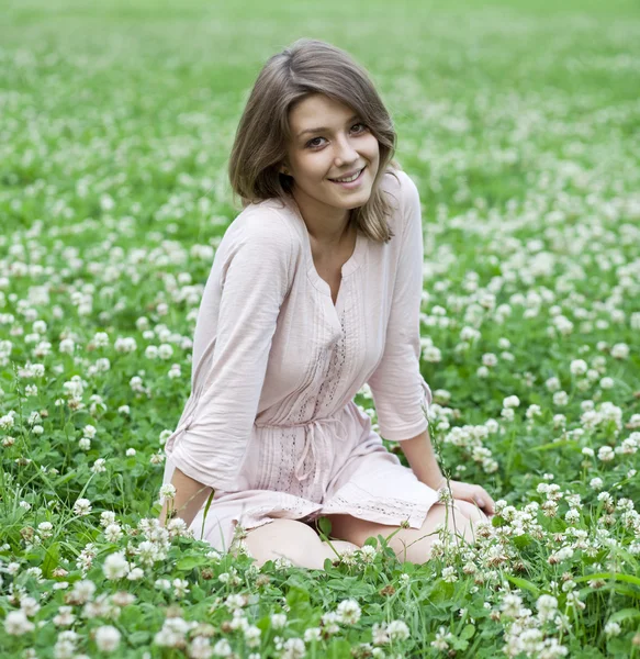 年轻女子坐在绿色的草坪上的肖像 — 图库照片