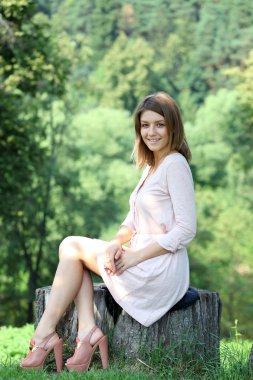 Portrait of young woman sitting in a summer park
