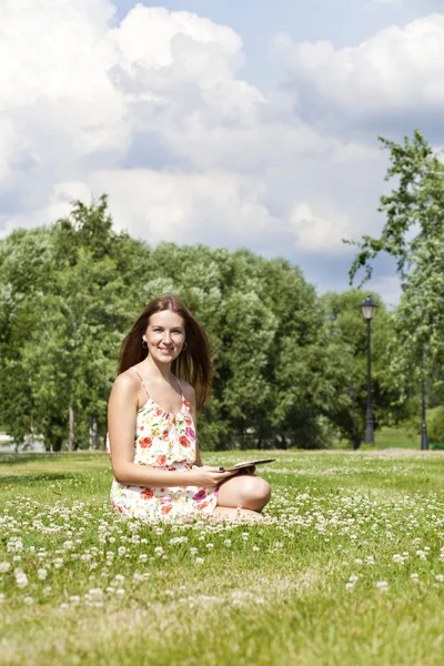 Portrait of young woman sitting on a green lawn — Stock Photo, Image