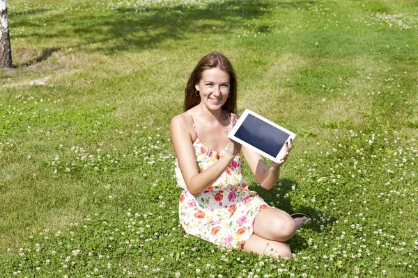 รูปภาพของหญิงสาวนั่งบนสนามหญ้าสีเขียว — ภาพถ่ายสต็อก