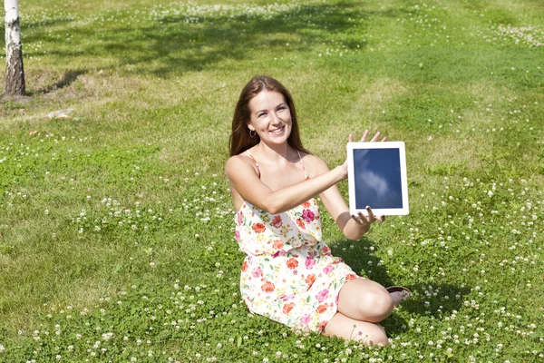 Portrait of young woman sitting on a green lawn — Stock Photo, Image