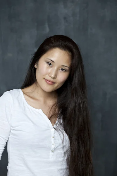 Asian young woman standing by wall — Stock Photo, Image