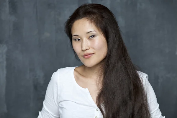 Asian young woman standing by wall — Stock Photo, Image