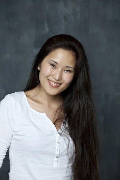 Asian young woman standing by wall — Stock Photo, Image