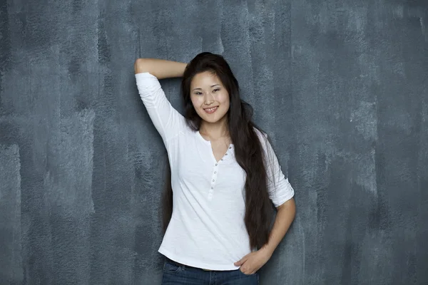 Asian young woman standing by wall — Stock Photo, Image