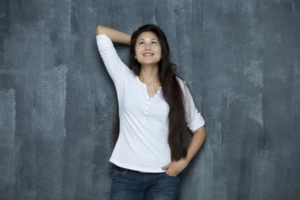 Aziatische jonge vrouw staande opzoeken door muur — Stockfoto