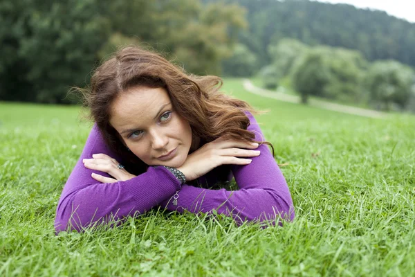 Портрет молодой женщины, лежащей на зеленой лужайке — стоковое фото