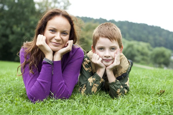 Mother and son lying on the green grass in the park — Stock Photo, Image