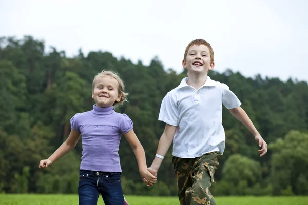 Bambini che corrono sull'erba verde nel parco — Foto Stock