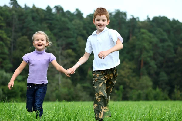 Crianças correndo na grama verde no parque — Fotografia de Stock