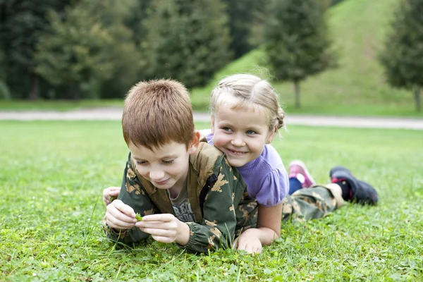 Děti leží na zelené trávě v parku — Stock fotografie