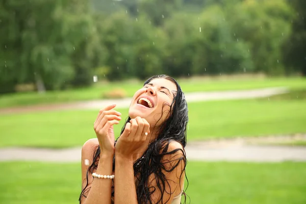 Jeune femme heureuse marchant sous la pluie — Photo