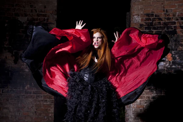 Terrible vampire woman in a red cloak — Stock Photo, Image