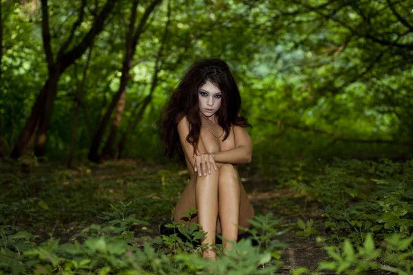 Mysterious naked girl sitting in a dark forest — Stock Photo, Image