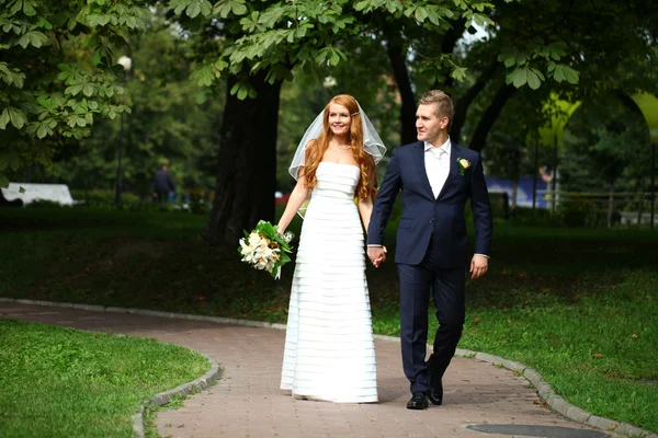 Happy bride and groom walking in the summer park — Stock Photo, Image