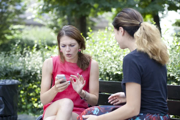 Jonge vrouw rustend op een bank in het park — Stockfoto