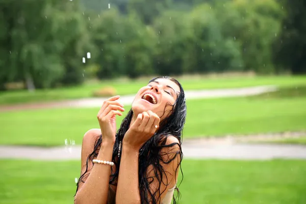 Jeune femme heureuse marchant sous la pluie — Photo