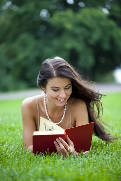 Jonge mooie jonge vrouw lezen van een boek buiten — Stockfoto