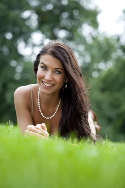 Porträt einer jungen Frau, die auf einem grünen Rasen liegt — Stockfoto
