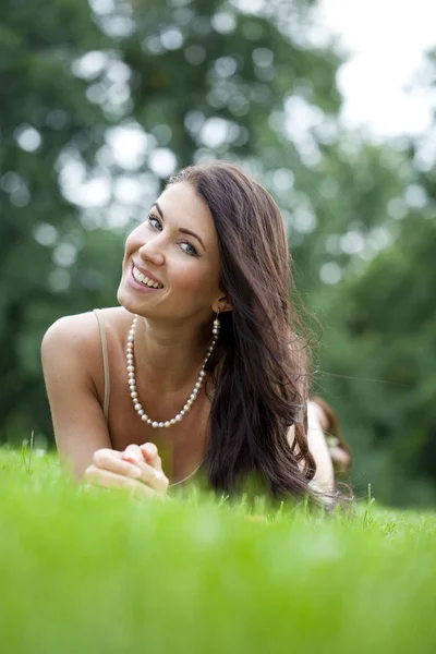 緑の芝生に横になっている若い女性の肖像画 — ストック写真