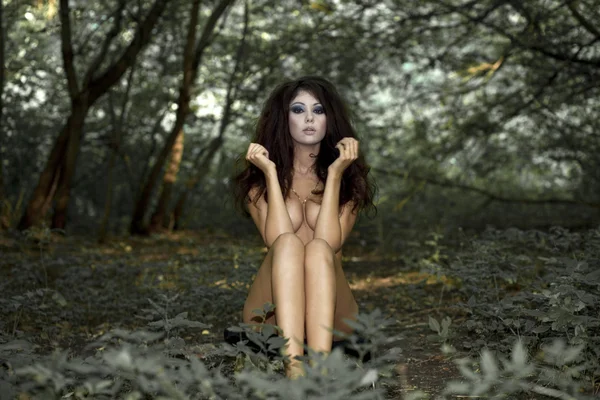Mysterious naked girl sitting in a dark forest — Stock Photo, Image