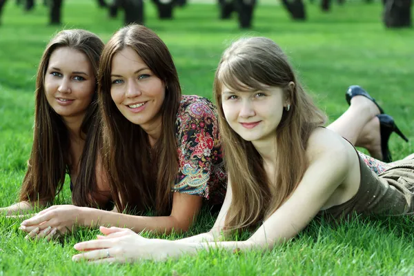 Three young women lying on a green lawn — Stock Photo, Image