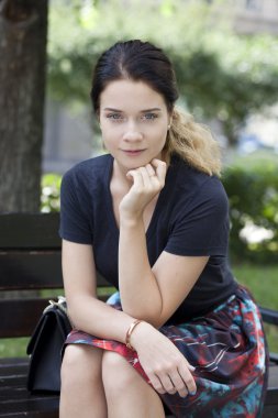 bir bankta oturan esmer