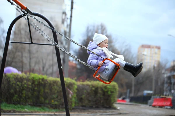 Маленькая девочка катается на качелях в парке — стоковое фото