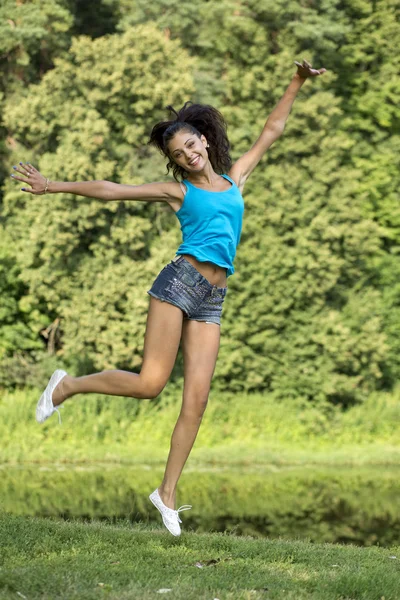 Beautiful girl jumping for joy in a summer park — Stock Photo, Image