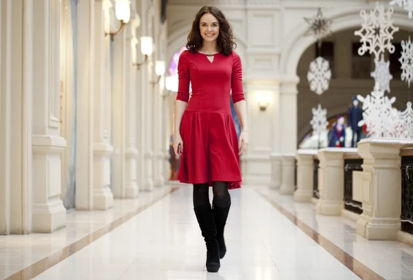 Kırmızı elbiseli genç güzel kadın mağaza yürür — Stok fotoğraf