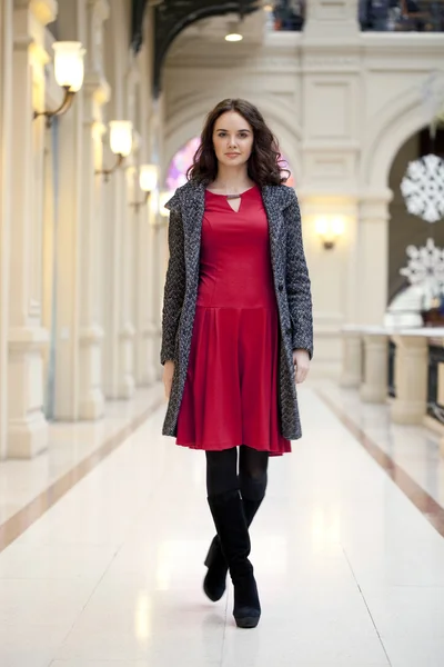 Jonge mooie vrouw in rode jurk wandelingen in de winkel — Stockfoto