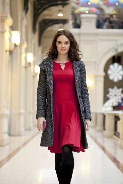 Young beautiful woman in red dress walks in the store — Stock Photo, Image