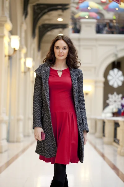 Jeune belle femme en robe rouge marche dans le magasin — Photo