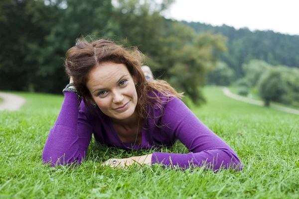 Ung kvinna liggande på en grön gräsmatta — Stockfoto