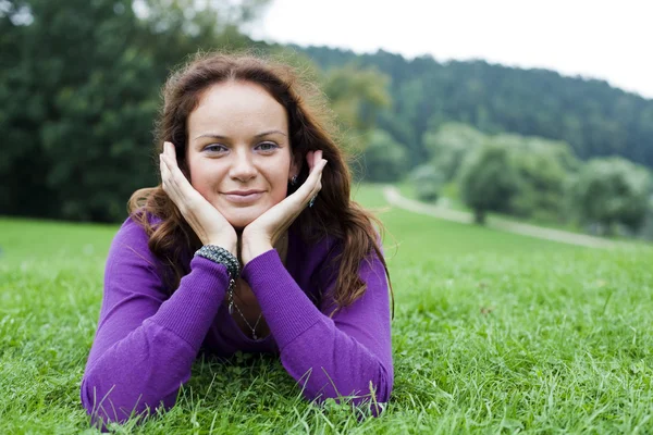 Young woman lying on a green lawn — Stock Photo, Image