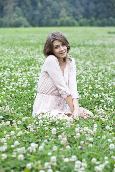 Mladá žena sedící na zeleném trávníku — Stock fotografie