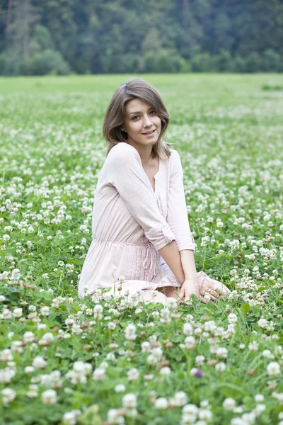 Jovem sentada em um gramado verde — Fotografia de Stock