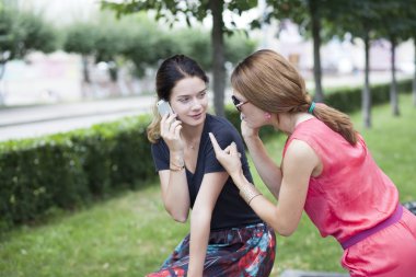 cep telefonu bir parkta bir bankta oturan genç kız gülümseyerek