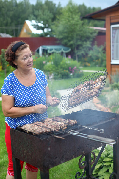 Woman Cooking On A Barbeque in the garden