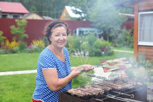Žena vaření na grilování v zahradě — Stock fotografie