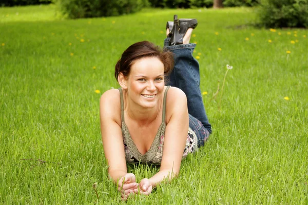 Young woman lying on a green lawn — Stock Photo, Image