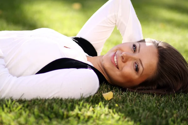 Молода жінка лежить на зеленому газоні — стокове фото