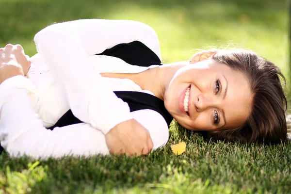 年轻女子躺在绿色的草坪上 — 图库照片