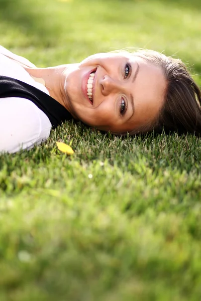 Jonge vrouw liggend op een groen gazon — Stockfoto