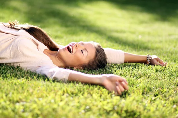 Jovem deitada em um gramado verde — Fotografia de Stock
