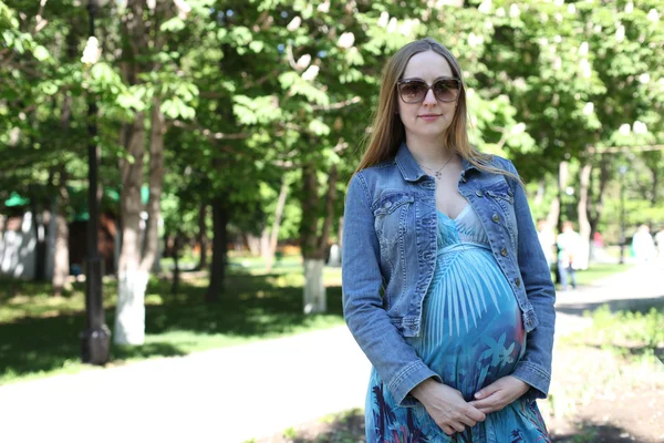 Молодая беременная женщина в летнем парке — стоковое фото